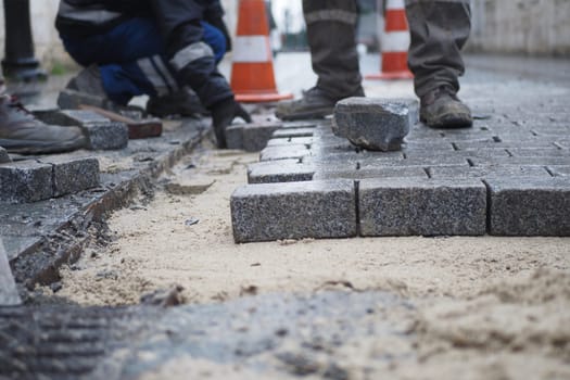 a worker laying concrete bricks on each other for building a new sidewalk.