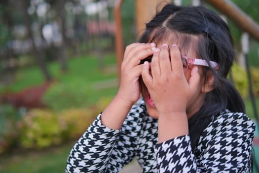 a upset child girl cover her face with hand .