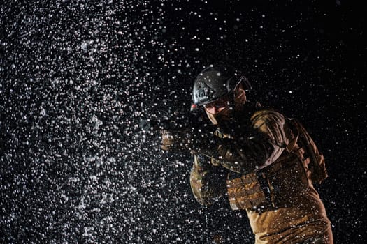 Army soldier in Combat Uniforms with an assault rifle, plate carrier and combat helmet going on a dangerous mission on a rainy night