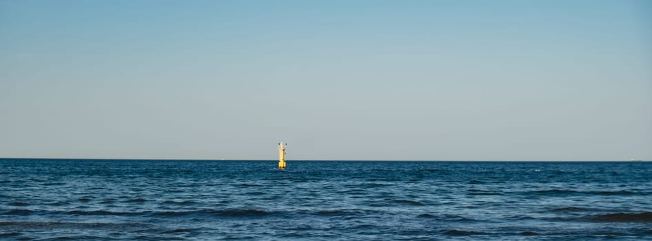 Yellow Lighthouse on blue sea line. Waves on sunny day on Baltic sea. Gdansk Poland. Coastline