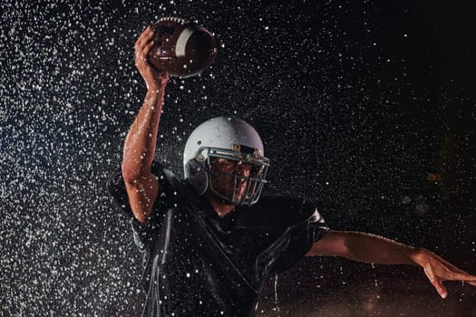 American Football Field: Lonely Athlete Warrior Standing on a Field Holds his Helmet and Ready to Play. Player Preparing to Run, Attack and Score Touchdown. Rainy Night with Dramatic Fog, Blue Light.