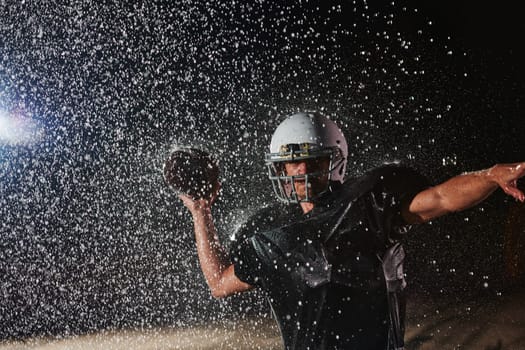 American Football Field: Lonely Athlete Warrior Standing on a Field Holds his Helmet and Ready to Play. Player Preparing to Run, Attack and Score Touchdown. Rainy Night with Dramatic Fog, Blue Light.