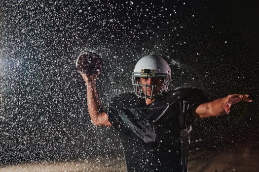 American Football Field: Lonely Athlete Warrior Standing on a Field Holds his Helmet and Ready to Play. Player Preparing to Run, Attack and Score Touchdown. Rainy Night with Dramatic Fog, Blue Light.