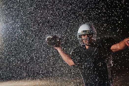 American Football Field: Lonely Athlete Warrior Standing on a Field Holds his Helmet and Ready to Play. Player Preparing to Run, Attack and Score Touchdown. Rainy Night with Dramatic Fog, Blue Light.