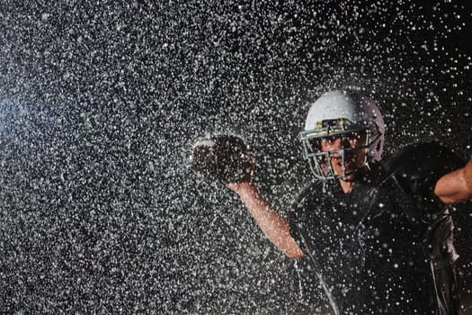 American Football Field: Lonely Athlete Warrior Standing on a Field Holds his Helmet and Ready to Play. Player Preparing to Run, Attack and Score Touchdown. Rainy Night with Dramatic Fog, Blue Light.