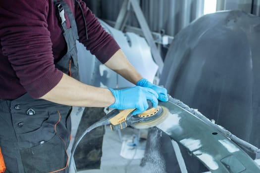 Repairing car body by puttying close up work after the accident by working sanding primer before painting. , The mechanic repair the car , Using plastic putty ,Prepare surface for spray painting