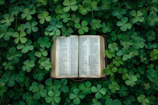 a bible book and a cross lying on the green clover leaves..