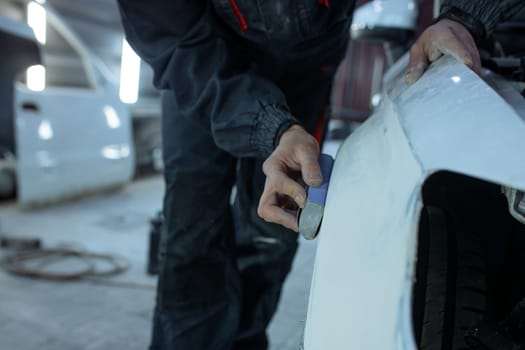 Repairing car body by puttying close up work after the accident by working sanding primer before painting. , The mechanic repair the car , Using plastic putty ,Prepare surface for spray painting