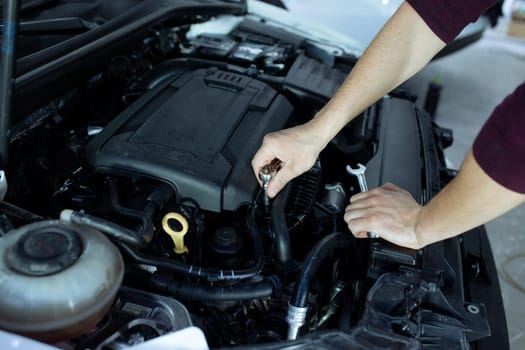 A male automech is inspecting the car's engine. Car service and car repair.