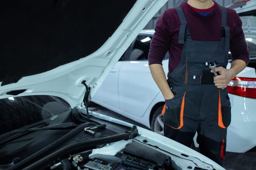 Car service. An auto mechanic is standing near the car with a tool in his hands. Vehicle technical inspection.