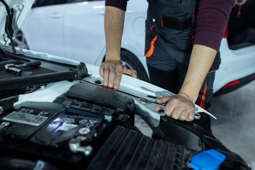 Car service. An auto mechanic is standing near the car with a tool in his hands. Vehicle technical inspection.