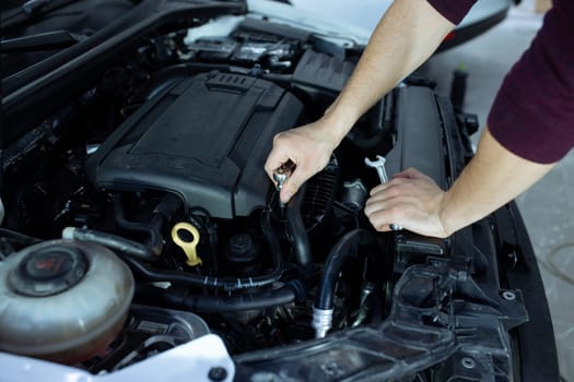 Car service. An auto mechanic is standing near the car with a tool in his hands. Vehicle technical inspection.