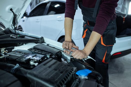 A male automech is inspecting the car's engine. Car service and car repair.