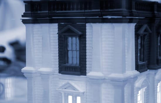 Model of building with white and black color, windows with light shining, created by 3D printer from molten plastic. Prototype printed on 3D printer brick building with columns and glowing windows.