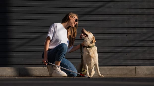 A blind woman walks her guide dog on the street. Girl hugging a labrador