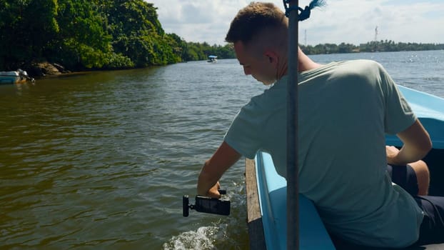 Man takes boat trip on phone. Action. Man shoots professionally on phone with tripod of travel. Man on tropical boat trip films trip.