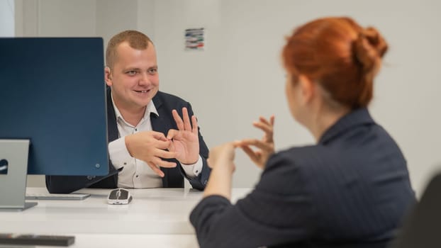 Business partners communicate in sign language. A deaf boss gives a task to a subordinate woman