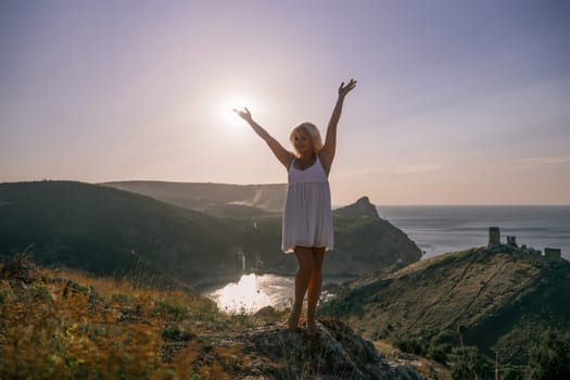 woman standing hill with her arms raised in the air, looking up at the sun. The scene is peaceful and serene, with the woman's expression conveying a sense of joy and happiness