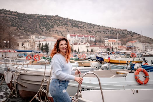 A woman stands in front of a row of boats, some of which have orange life preservers on them. The scene is peaceful and serene, with the boats and the woman creating a sense of calmness and relaxation