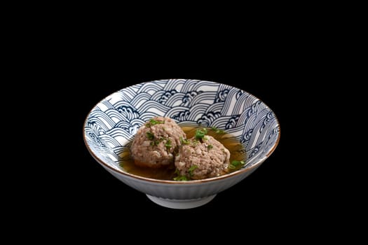 Tasty scalded meatball with coriander in a bowl on black background. Asian food.