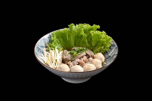 Thai noodles soup with boiled pork offal and vegetables serve in bowl on black background. Asian food concept.