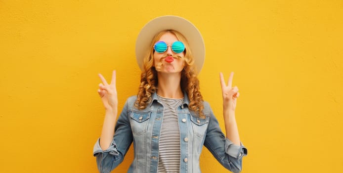 Portrait of stylish funny young woman showing mustache her hair blowing lips with red lipstick wearing summer straw hat on yellow background