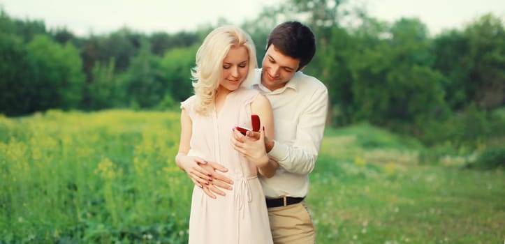 Wedding concept, happy lovely young couple, man proposing a ring to his beloved woman outdoors in summer park