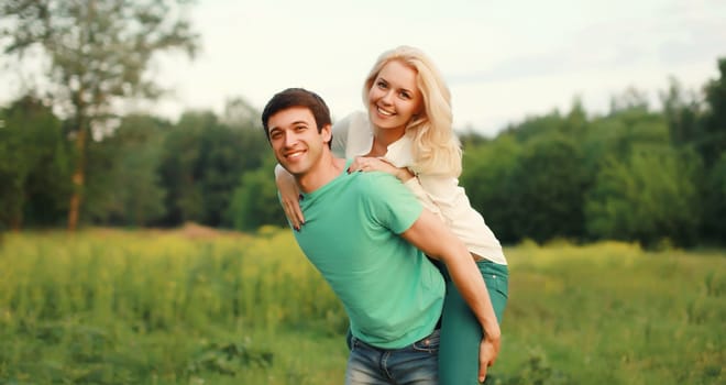 Portrait of beautiful happy smiling young couple in love together hugging in green summer park