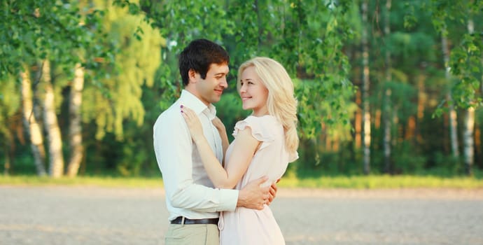 Portrait of beautiful happy smiling young couple in love together hugging in green summer park