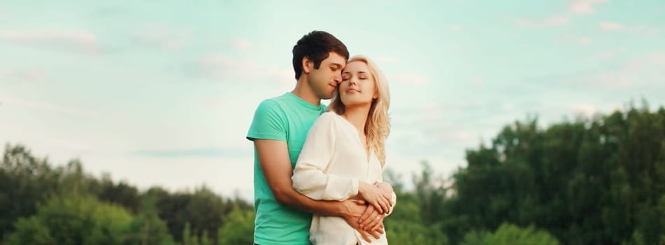 Portrait of beautiful happy smiling young couple in love together hugging in green summer park