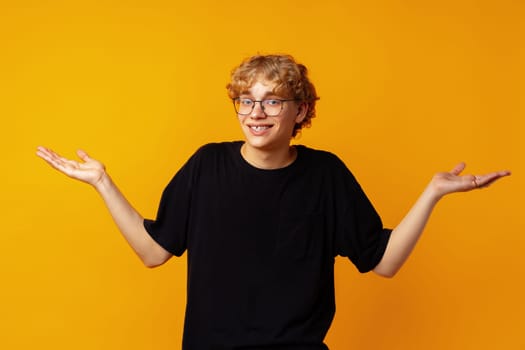 Clueless man in black t-shirt shrugging, dont know anything standing over yellow background close up