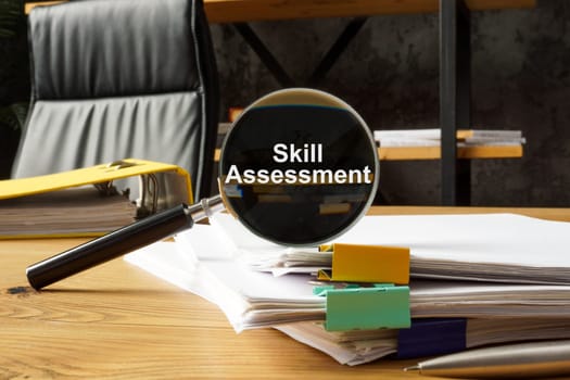 Skill assessment concept. A stack of papers and magnifying glass with an inscription.