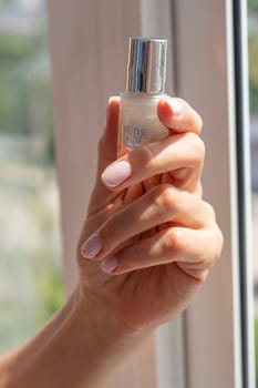 Shot of the beautiful woman's hand holding bottle of nail enamel