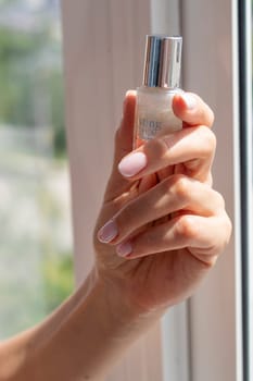 Shot of the beautiful woman's hand holding bottle of nail enamel