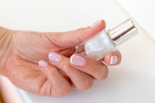 Shot of the beautiful woman's hand holding bottle of nail enamel