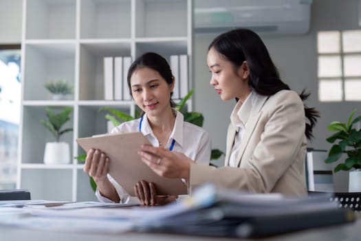 Businesswomen reviewing documents in modern office. Concept of teamwork and collaboration.