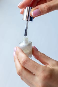 Shot of the beautiful woman's hand holding bottle of nail enamel