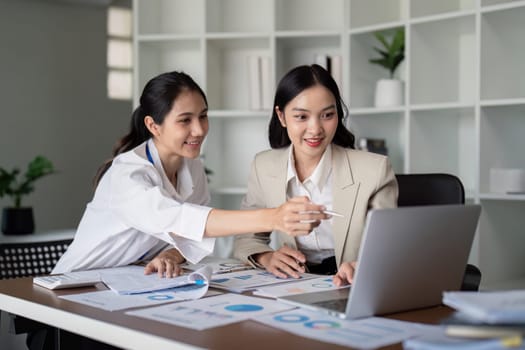 Businesswomen working on laptop and analyzing data in office. Concept of teamwork and collaboration.