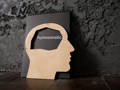 A dark notepad with an inscription psychosomatic and an outline of head.