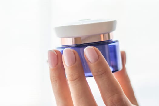 Shot of the beautiful woman's hand holding bottle of skin care product.