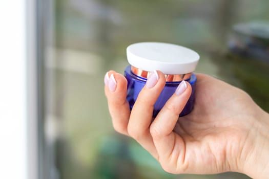 Shot of the beautiful woman's hand holding bottle of skin care product.