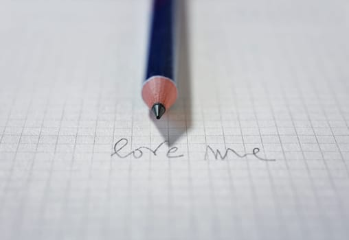 Sheet of white  paper  with handwritten words LOVE ME with pencil , couple relationship