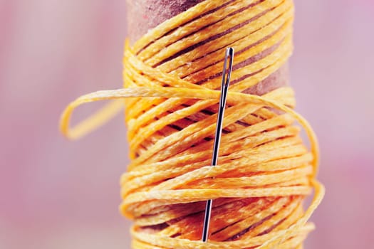 Detail of  yellow thread  and needle  on spool, dressmaker at work ,