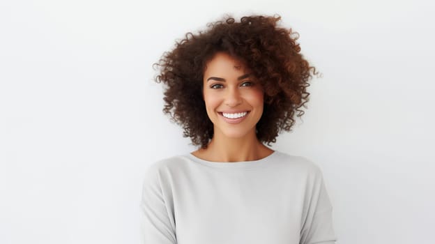 Portrait of beautiful happy smiling young woman with toothy smile, curly hair, looking at camera on white studio background