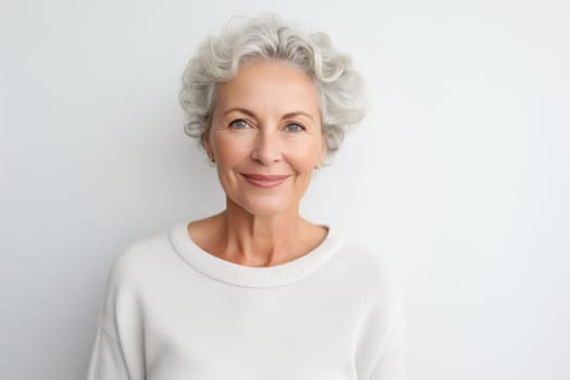 Portrait of beautiful happy smiling mature woman with gray hair looking at camera on white studio background