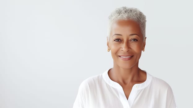 Portrait of beautiful happy smiling african mature woman with gray hair looking at camera on white studio background