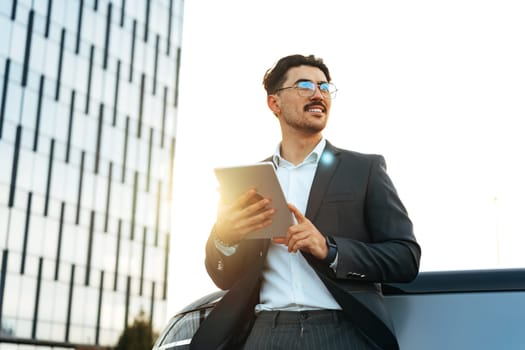 Young businessman using digital tablet while standing outdoors close up