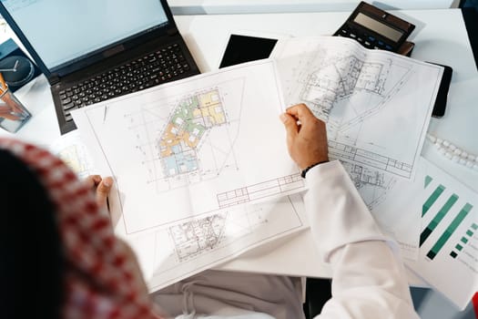 Unrecognizable arab businessman in traditional outfit working at the table in office close up