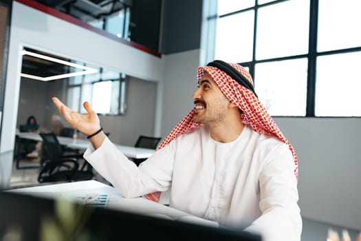 Young muslim businessman in traditional outfit working at the table in office clsoe up