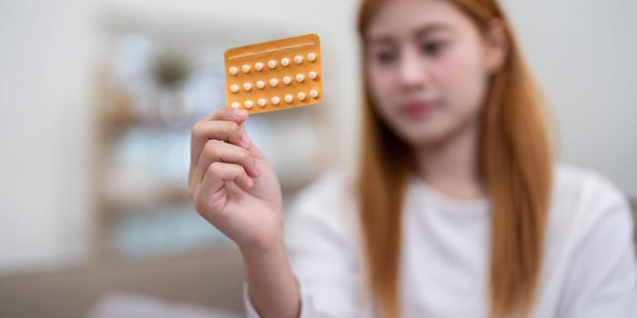 Woman examining a pack of birth control pills. Concept of contraception and reproductive health.